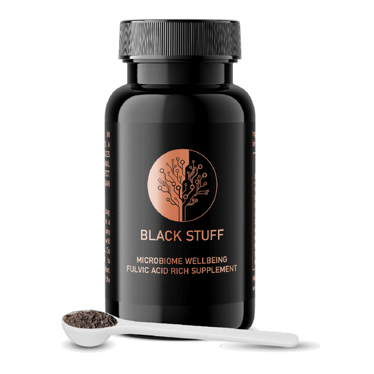 A black bottle labeled 'BLACK STUFF' with a gold tree logo, alongside a white dosing scoop filled with black powder.